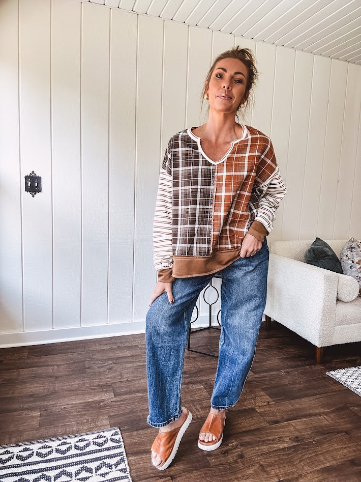 Plaid pullover pairs earth-tone mocha, cream, and rust with playful contrasting stripes on the sleeves with a split neck and relaxed fit.