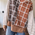 Plaid pullover pairs earth-tone mocha, cream, and rust with playful contrasting stripes on the sleeves with a split neck and relaxed fit.