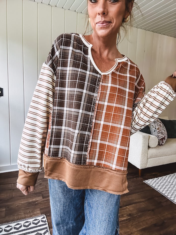 Plaid pullover pairs earth-tone mocha, cream, and rust with playful contrasting stripes on the sleeves with a split neck and relaxed fit.