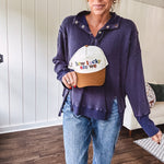 Cream canvas trucker hat with tan bill and multi colored puff embroidered lettering on the front.
