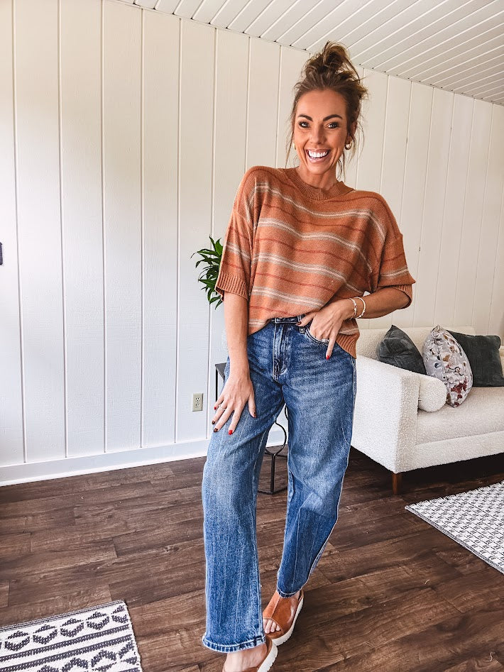 High-rise fit with a curved, architectural leg, rigid denim front, stretch fabric, top block, curved outer seam, and tapered hem that create a modern "barrel" or "horseshoe" shape sitting away from the leg.