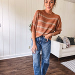 Lightweight, striped drop shoulder sweater tee in a soft sage or rust base  with warm stripes of light brown, taupe, and spice, and ribbed detailing at the neck, cuffs, and hem.
