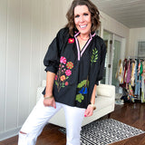 Black cotton top with mock collar and V neck, 3/4 balloon sleeves, pink trim at the neck and bright embroidered pink, green and blue florals.