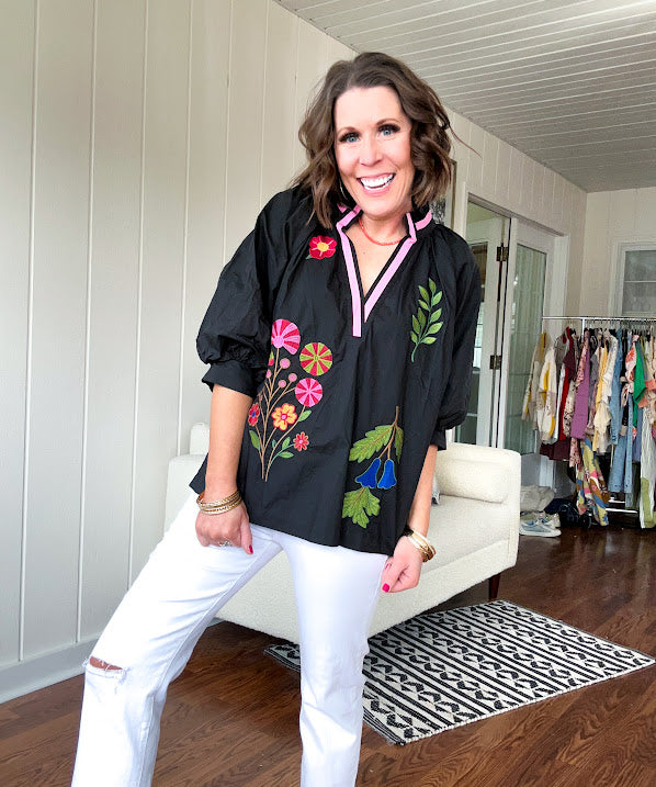 Black cotton top with mock collar and V neck, 3/4 balloon sleeves, pink trim at the neck and bright embroidered pink, green and blue florals.