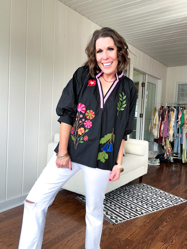 Black cotton top with mock collar and V neck, 3/4 balloon sleeves, pink trim at the neck and bright embroidered pink, green and blue florals.