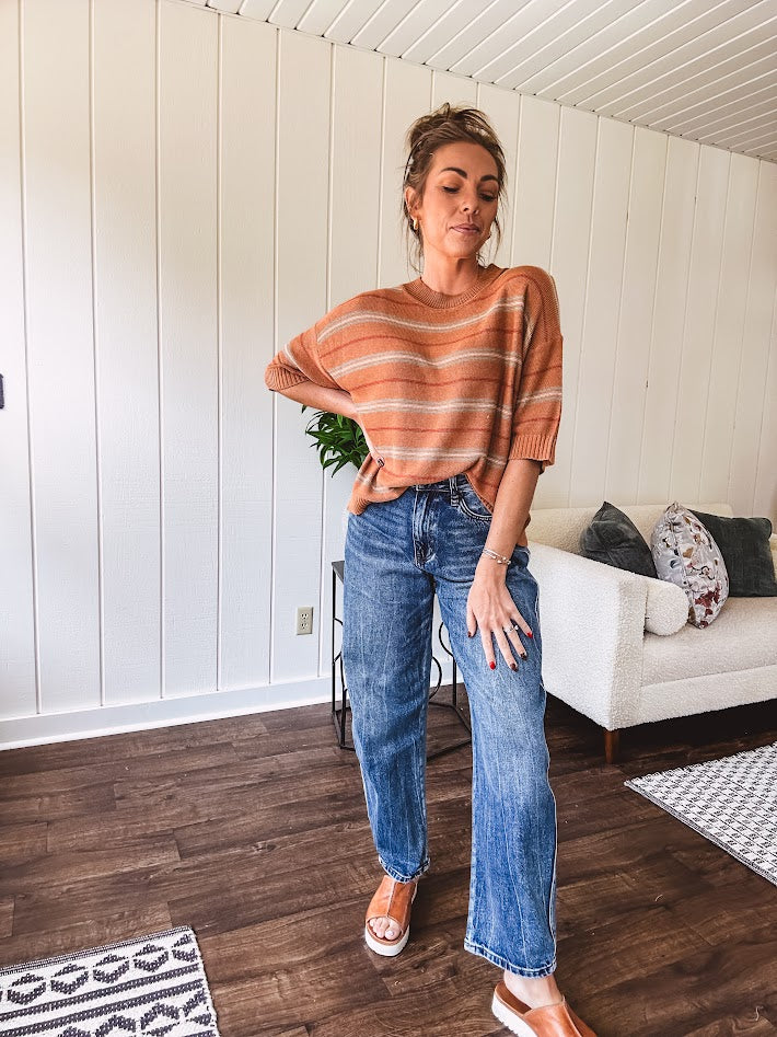 High-rise fit with a curved, architectural leg, rigid denim front, stretch fabric, top block, curved outer seam, and tapered hem that create a modern "barrel" or "horseshoe" shape sitting away from the leg.
