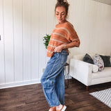 High-rise fit with a curved, architectural leg, rigid denim front, stretch fabric, top block, curved outer seam, and tapered hem that create a modern "barrel" or "horseshoe" shape sitting away from the leg.