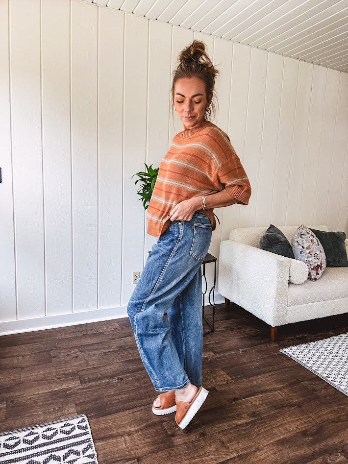 Lightweight, striped drop shoulder sweater tee in a soft sage or rust base  with warm stripes of light brown, taupe, and spice, and ribbed detailing at the neck, cuffs, and hem.