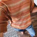 Lightweight, striped drop shoulder sweater tee in a soft sage or rust base  with warm stripes of light brown, taupe, and spice, and ribbed detailing at the neck, cuffs, and hem.