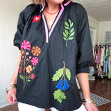 Black cotton top with mock collar and V neck, 3/4 balloon sleeves, pink trim at the neck and bright embroidered pink, green and blue florals.