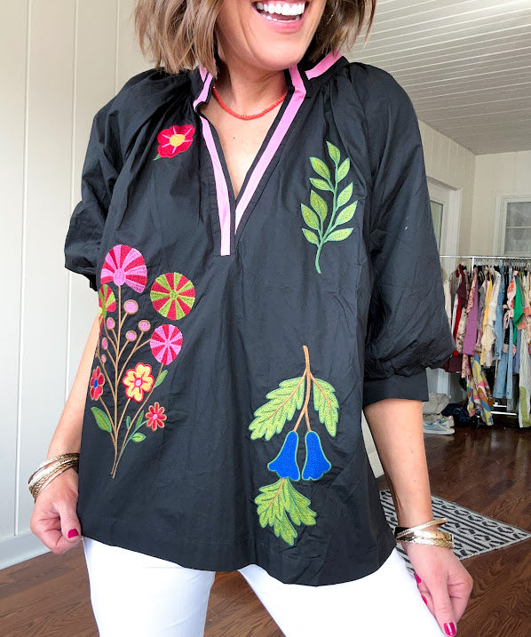 Black cotton top with mock collar and V neck, 3/4 balloon sleeves, pink trim at the neck and bright embroidered pink, green and blue florals.