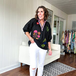 Black cotton top with mock collar and V neck, 3/4 balloon sleeves, pink trim at the neck and bright embroidered pink, green and blue florals.