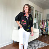 Black cotton top with mock collar and V neck, 3/4 balloon sleeves, pink trim at the neck and bright embroidered pink, green and blue florals.