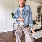 Medium wash non-stretch denim jacket with classic trim, raw, uneven hem and cuffs with silver hardware and cropped length.