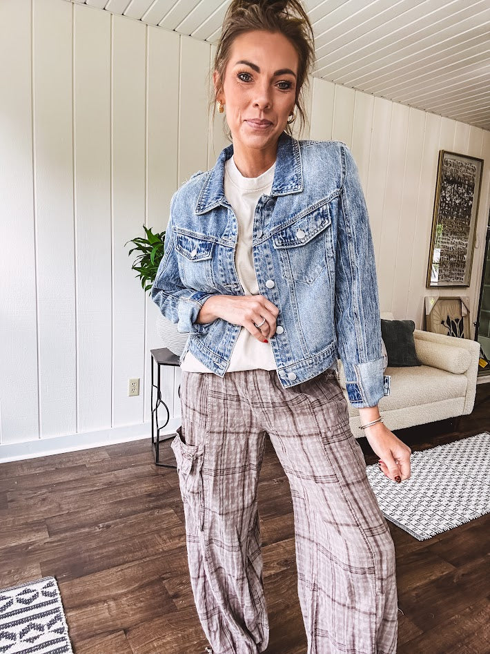 Medium wash non-stretch denim jacket with classic trim, raw, uneven hem and cuffs with silver hardware and cropped length.