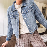 Medium wash non-stretch denim jacket with classic trim, raw, uneven hem and cuffs with silver hardware and cropped length.