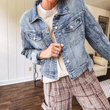 Medium wash non-stretch denim jacket with classic trim, raw, uneven hem and cuffs with silver hardware and cropped length.