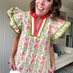 White cotton blouse with coral and lime florals and stripes at the ruffled collar and V neck, flutter sleeves with lime trim, flowy hem.