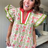 White cotton blouse with coral and lime florals and stripes at the ruffled collar and V neck, flutter sleeves with lime trim, flowy hem.