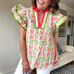 White cotton blouse with coral and lime florals and stripes at the ruffled collar and V neck, flutter sleeves with lime trim, flowy hem.