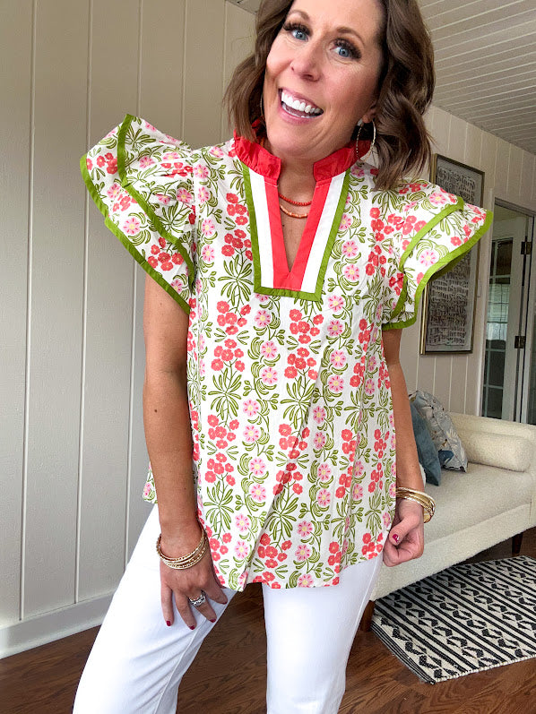 White cotton blouse with coral and lime florals and stripes at the ruffled collar and V neck, flutter sleeves with lime trim, flowy hem.