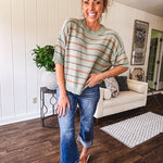 Lightweight, striped drop shoulder sweater tee in a soft sage or rust base  with warm stripes of light brown, taupe, and spice, and ribbed detailing at the neck, cuffs, and hem.