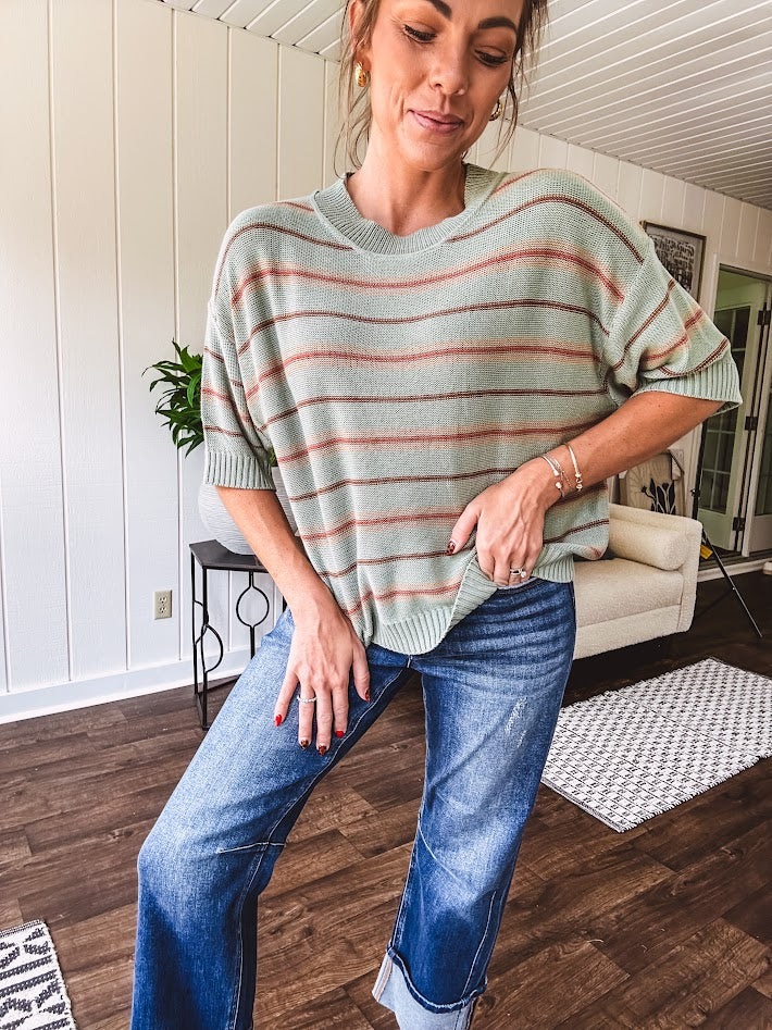 Lightweight, striped drop shoulder sweater tee in a soft sage or rust base  with warm stripes of light brown, taupe, and spice, and ribbed detailing at the neck, cuffs, and hem.