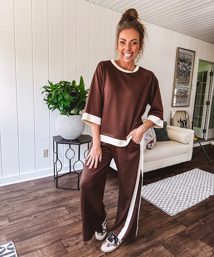 Cocoa brown super soft set with ivory trim at the round neck, cuffs and pleated side trim on the matching pants with elastic waist and pockets. 3/4 sleeve, oversized fit.