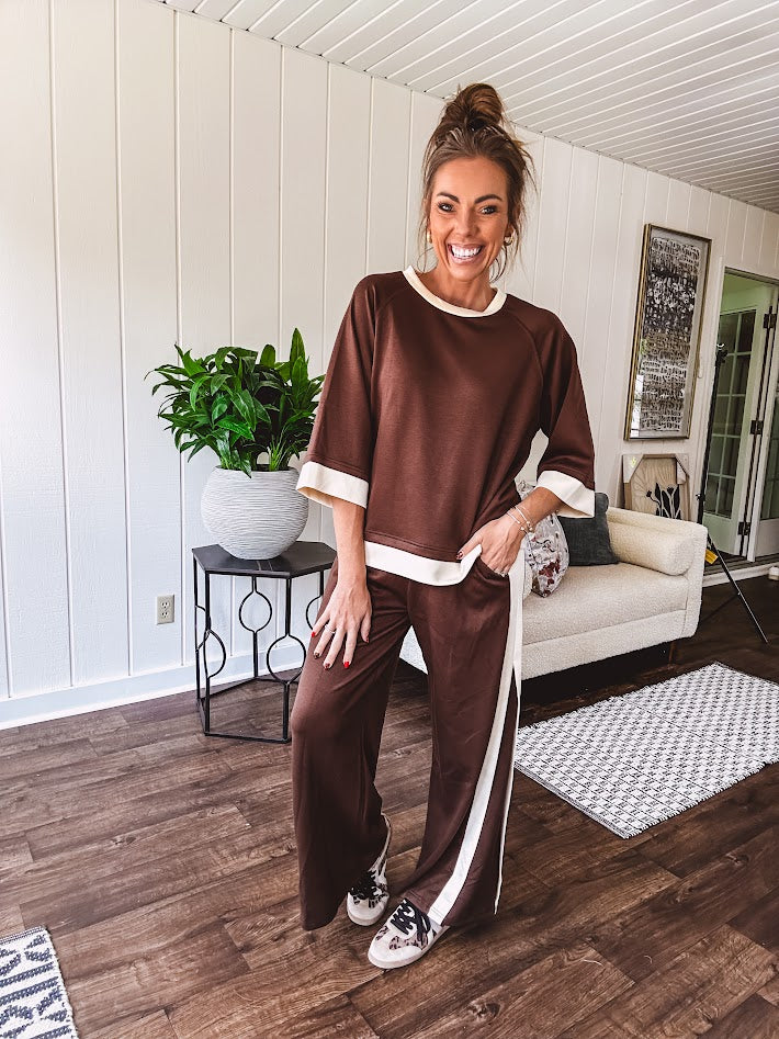 Cocoa brown super soft set with ivory trim at the round neck, cuffs and pleated side trim on the matching pants with elastic waist and pockets. 3/4 sleeve, oversized fit.