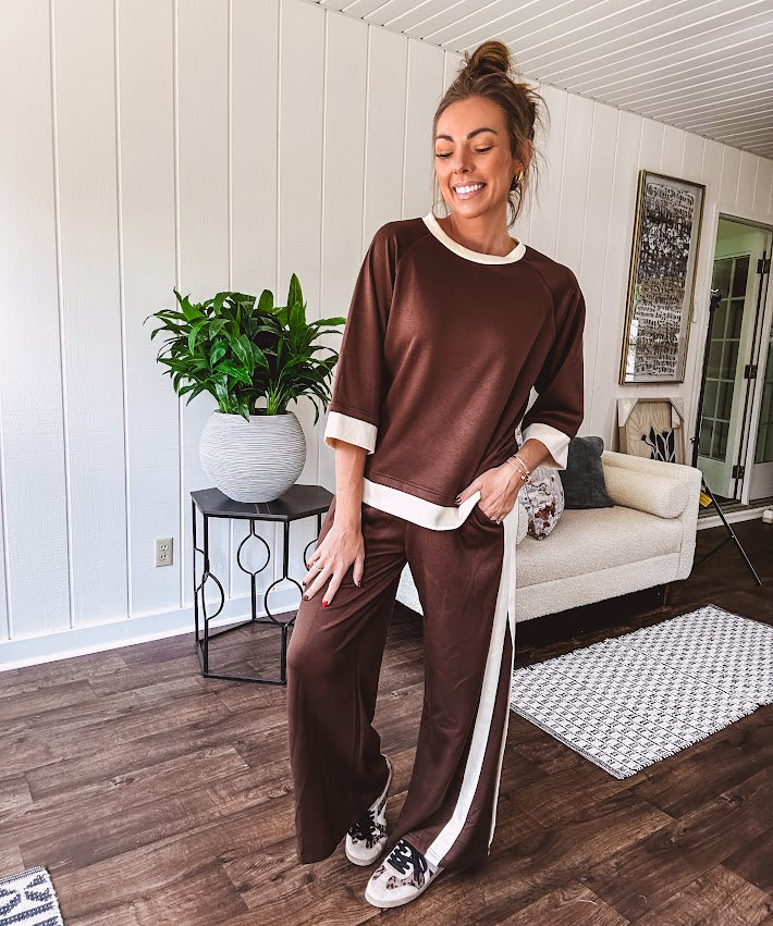 Cocoa brown super soft set with ivory trim at the round neck, cuffs and pleated side trim on the matching pants with elastic waist and pockets. 3/4 sleeve, oversized fit.
