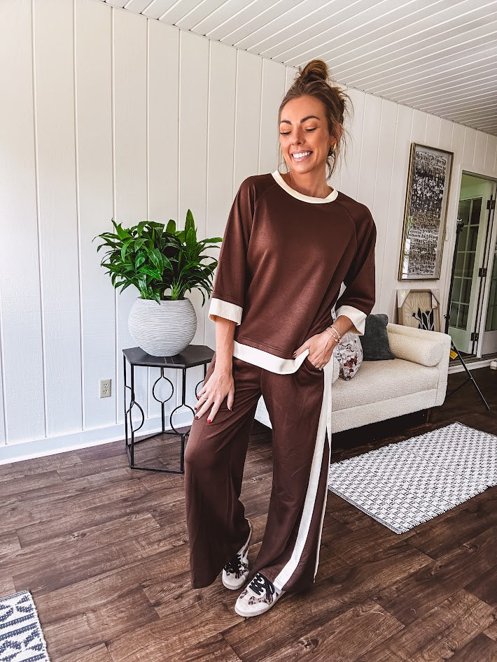 Cocoa brown super soft set with ivory trim at the round neck, cuffs and pleated side trim on the matching pants with elastic waist and pockets. 3/4 sleeve, oversized fit.