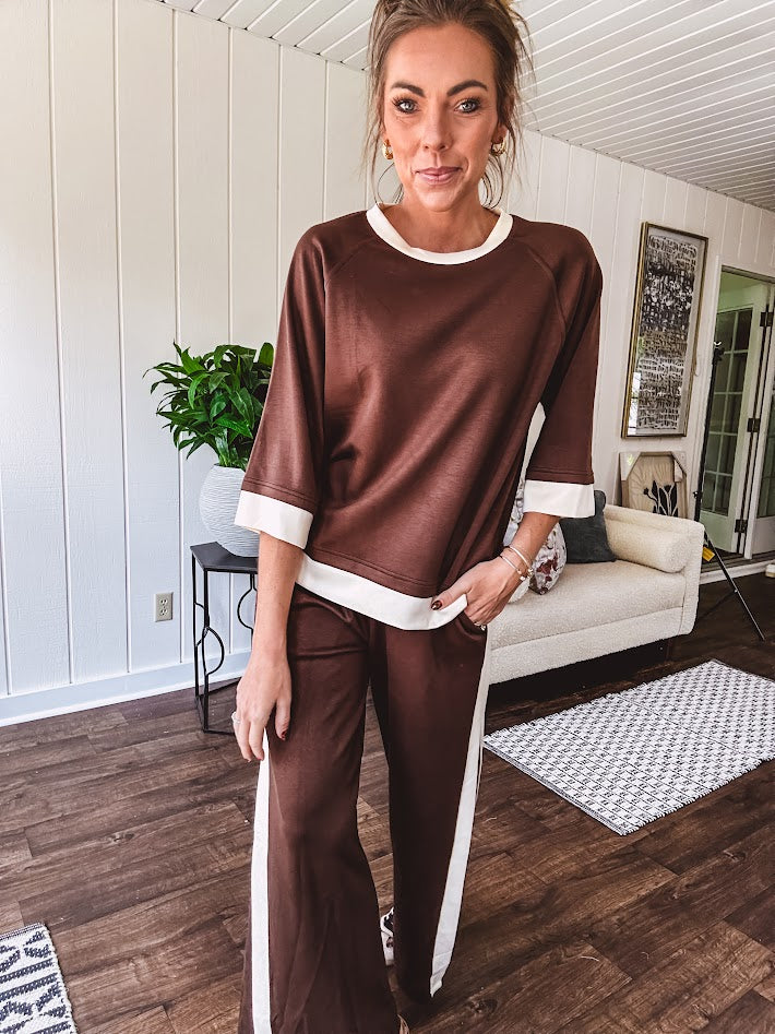 Cocoa brown super soft set with ivory trim at the round neck, cuffs and pleated side trim on the matching pants with elastic waist and pockets. 3/4 sleeve, oversized fit.