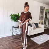 Cocoa brown super soft set with ivory trim at the round neck, cuffs and pleated side trim on the matching pants with elastic waist and pockets. 3/4 sleeve, oversized fit.