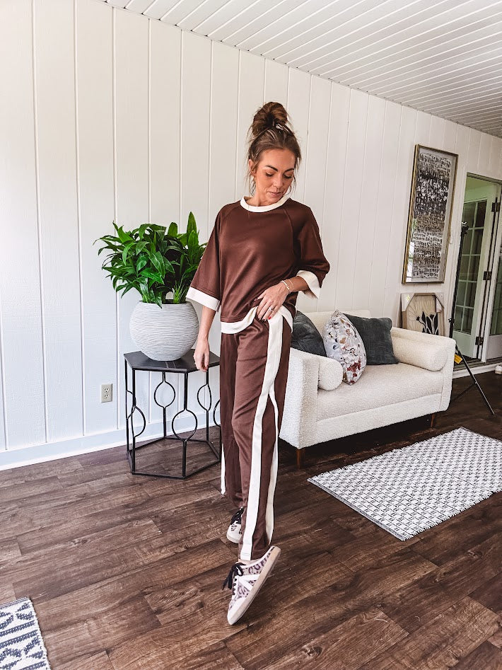 Cocoa brown super soft set with ivory trim at the round neck, cuffs and pleated side trim on the matching pants with elastic waist and pockets. 3/4 sleeve, oversized fit.