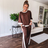 Cocoa brown super soft set with ivory trim at the round neck, cuffs and pleated side trim on the matching pants with elastic waist and pockets. 3/4 sleeve, oversized fit.