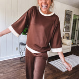 Cocoa brown super soft set with ivory trim at the round neck, cuffs and pleated side trim on the matching pants with elastic waist and pockets. 3/4 sleeve, oversized fit.