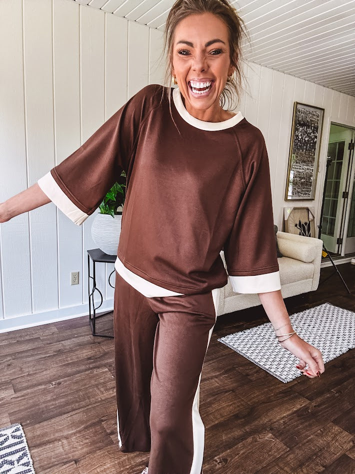 Cocoa brown super soft set with ivory trim at the round neck, cuffs and pleated side trim on the matching pants with elastic waist and pockets. 3/4 sleeve, oversized fit.