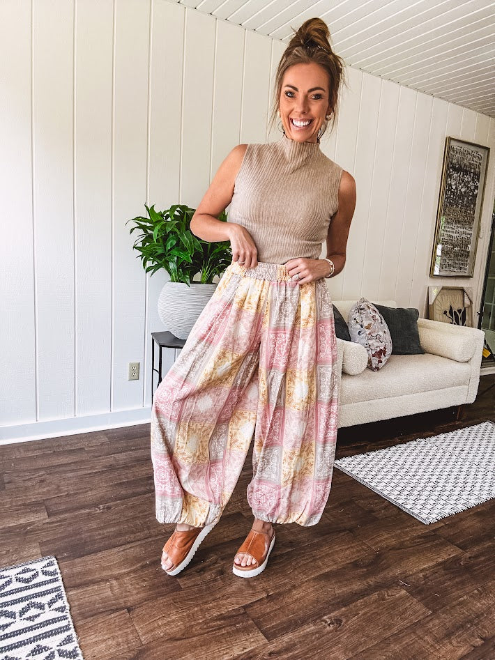 Lightweight cotton balloon style pants with elastic waist and cuffs, side pockets and pastel taupe, pink and coral paisley bandana print.