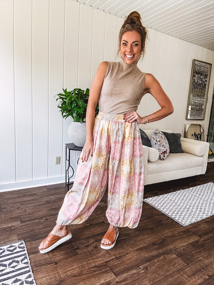 Lightweight cotton balloon style pants with elastic waist and cuffs, side pockets and pastel taupe, pink and coral paisley bandana print.