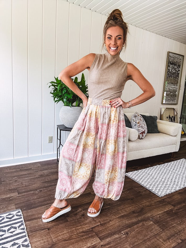 Lightweight cotton balloon style pants with elastic waist and cuffs, side pockets and pastel taupe, pink and coral paisley bandana print.