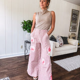 Lightweight blush and cream pinstripe ultra wide leg pants with oversized rose appliques throughout, button and zipper closure with elastic back at the waist, side and back pockets.