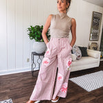 Lightweight blush and cream pinstripe ultra wide leg pants with oversized rose appliques throughout, button and zipper closure with elastic back at the waist, side and back pockets.