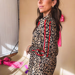 Leo print gold metallic button down dress with red stripes on the sleeves. Metal buttons, a collar, and functional pockets