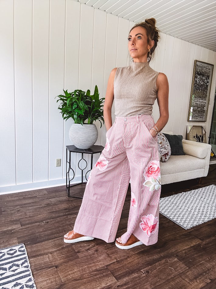 Lightweight blush and cream pinstripe ultra wide leg pants with oversized rose appliques throughout, button and zipper closure with elastic back at the waist, side and back pockets.