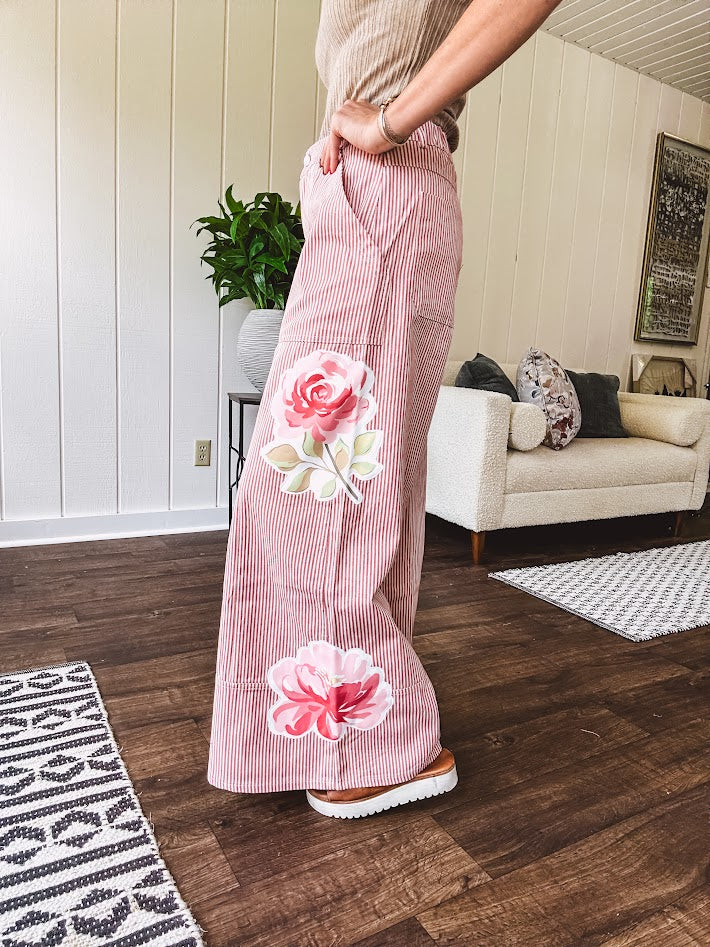 Lightweight blush and cream pinstripe ultra wide leg pants with oversized rose appliques throughout, button and zipper closure with elastic back at the waist, side and back pockets.