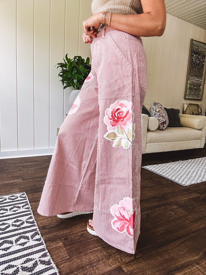 Lightweight blush and cream pinstripe ultra wide leg pants with oversized rose appliques throughout, button and zipper closure with elastic back at the waist, side and back pockets.