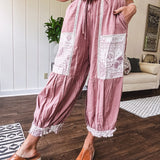 Soft, lightweight cotton pants that blend rose and grey plaid with creamy floral patchwork, lacey cream crochet trim, and a patchwork-trimmed ruffled hemline. Elastic drawstring waist and wide-leg silhouette with lace at the cuffs.