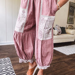 Soft, lightweight cotton pants that blend rose and grey plaid with creamy floral patchwork, lacey cream crochet trim, and a patchwork-trimmed ruffled hemline. Elastic drawstring waist and wide-leg silhouette with lace at the cuffs.