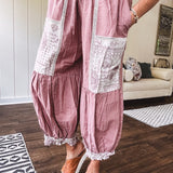 Soft, lightweight cotton pants that blend rose and grey plaid with creamy floral patchwork, lacey cream crochet trim, and a patchwork-trimmed ruffled hemline. Elastic drawstring waist and wide-leg silhouette with lace at the cuffs.