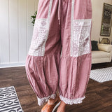 Soft, lightweight cotton pants that blend rose and grey plaid with creamy floral patchwork, lacey cream crochet trim, and a patchwork-trimmed ruffled hemline. Elastic drawstring waist and wide-leg silhouette with lace at the cuffs.